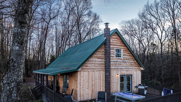 Une cabane en rondins dotée d’une terrasse, de meubles de jardin et d’une table de billard.