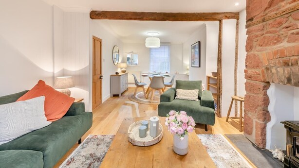 A cozy living room with a green sofa, a coffee table with decorative items, and a brick fireplace.