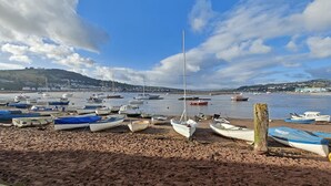 A beach with boats and a distant bridge.