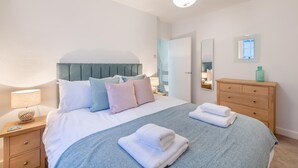 A neatly arranged bedroom with a bed, bedside tables, a dresser, and a mirror.