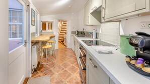 A compact kitchen with a wooden countertop, a built-in oven, and a coffee machine.