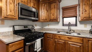 A kitchen with wooden cabinets, a stainless steel microwave, a gas stove, and a granite countertop. - Native Charm Adobe Guesthouse in Historic Old Town with wifi, AC, patio grill. (albuquerque)