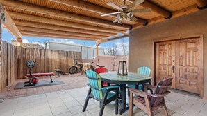 An outdoor patio with a wooden ceiling, a table with chairs, a bicycle, and a weight bench. - Native Charm Adobe Guesthouse in Historic Old Town with wifi, AC, patio grill. (albuquerque)