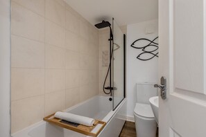 A modern bathroom with a bathtub, shower, and toilet.