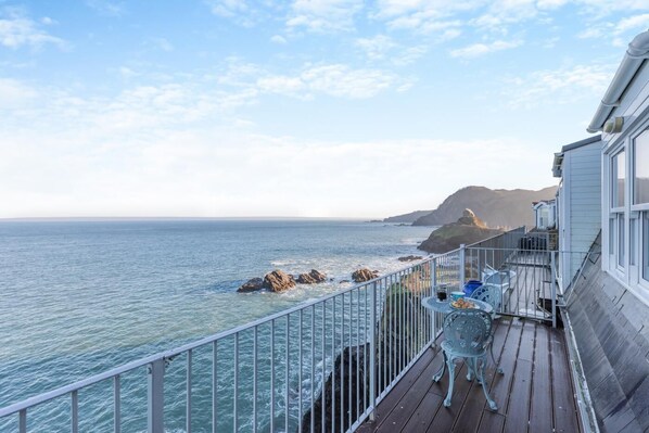 A balcony with a view of the ocean and a rocky coastline.