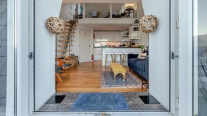 A modern interior with a staircase leading to a loft bedroom, a dining area, and a kitchen. - 2 Bed in Ilfracombe (oc-o30532) (Ilfracombe)