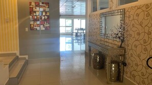 A hallway with a tiled floor, a staircase, a wall with a decorative mirror, and a window with a view of the outside. - Hotel Tijerinos (Boaco)
