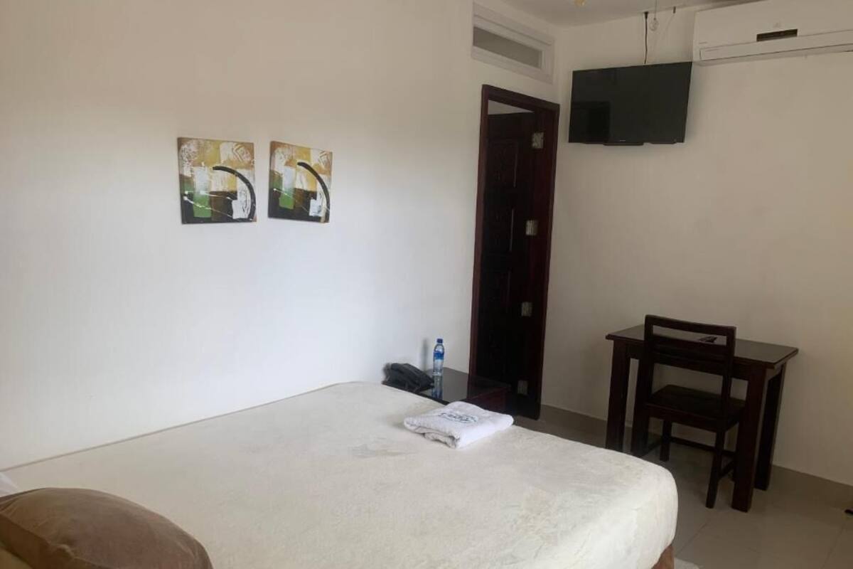 A hotel room with a bed, a desk, and a TV mounted on the wall.