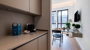 Una cocina moderna con una cafetera, un bol de fruta y un comedor con una mesa y sillas.
