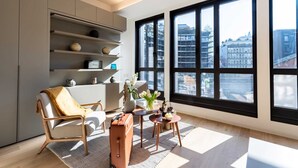 Una sala de estar moderna con un ventanal grande, un sofá, una mesita de centro y una maleta.