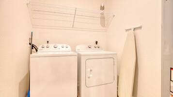 Una sala de lavandería con dos lavadoras blancas y un tendedero.