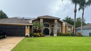 A residential house with a garage, a well-maintained lawn, and a front door with a decorative arch. - All Amenities of home! Centrally located, family friendly & ideal entertaining (Port St. Lucie)
