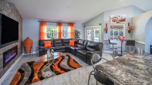 A modern living room with a sectional sofa, a fireplace, and a dining area with a table and chairs. - All Amenities of home! Centrally located, family friendly & ideal entertaining (Port St. Lucie)