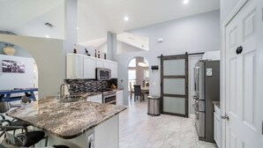 A modern kitchen with granite countertops, white cabinets, and stainless steel appliances. - All Amenities of home! Centrally located, family friendly & ideal entertaining (Port St. Lucie)