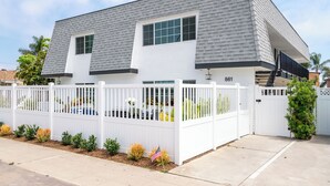A two-story house with a white exterior, a grey roof, and a white fence with a mailbox. - Stunning Family Getaway - One Block from Beach, Fast WiFi, A/C, BBQ, Parking (San Diego)