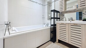 Une salle de bain moderne avec une grande baignoire, un meuble-lavabo en bois et un miroir au-dessus du lavabo.