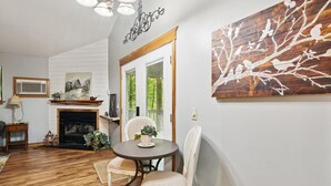 A cozy living room with a fireplace, a dining table with chairs, and a large wall art piece. - Wildflower (Sautee Nacoochee)