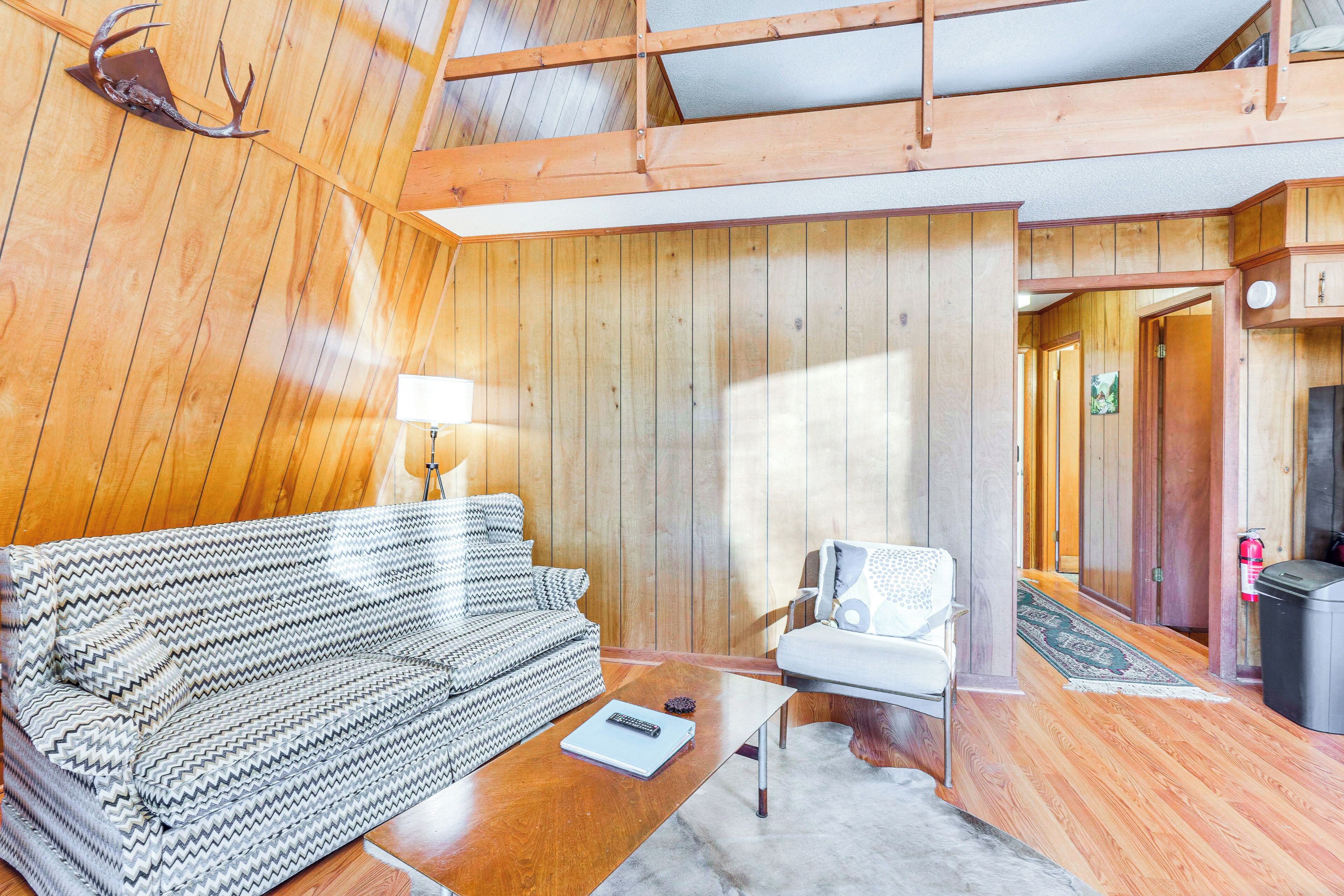A wooden interior with a sofa, a chair, and a table.