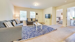A living room with a grey sofa, a patterned rug, a white coffee table, and a TV on the wall. - 9 Mi to Shore: Family-Friendly Sunset Beach Home (Sunset Beach)