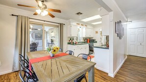 Ein Essbereich mit Holztisch, Stühlen, Deckenventilator und einer Küche im Hintergrund.