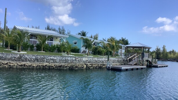 A waterfront property with a dock, a covered area, and a house with a metal roof.