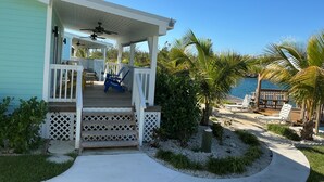 A beachfront property with a covered porch, outdoor seating, and a view of the ocean.
