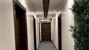 Ein Korridor mit Teppichböden, Holztüren und einer dekorativen Decke.