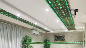 Eine großzügige Lobby mit roten und beigen Sofas, einem Marmorboden und grüner Dekoleuchtung.