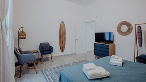 A hotel room with a bed, a TV, a surfboard, a chair, and a desk. - Casa Lucia by Monholiday (Monopoli)