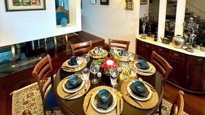 Ein Esszimmer mit einem runden Tisch, gedeckt für sechs Personen, umgeben von Holzstühlen.