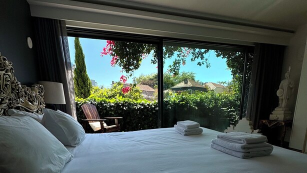 Ein Hotelzimmer mit einem großen Bett, Blick auf Grünflächen und Gebäude und einer Statue auf dem Nachttisch.