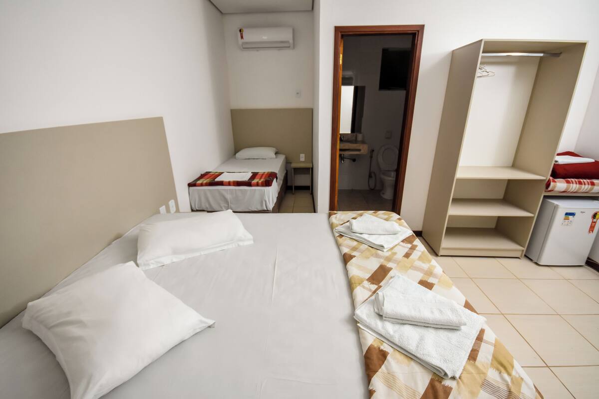 Une chambre avec deux lits, une armoire, une petite table et un réfrigérateur.