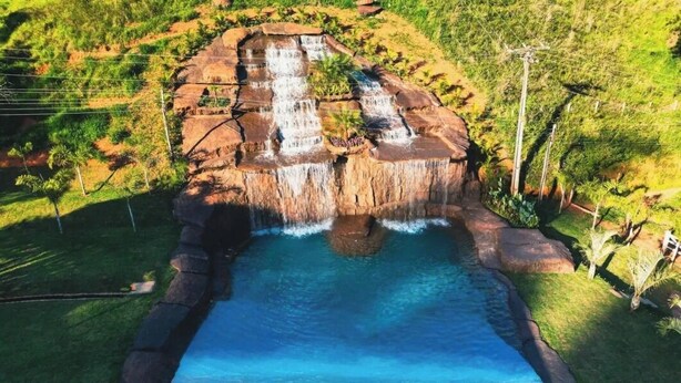 A waterfall cascading into a pool surrounded by lush greenery and rocky terrain. - Hotel Fazenda Bavária (Pouso Alto)