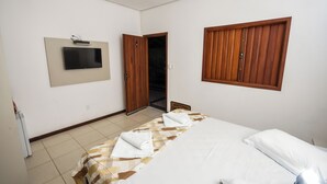 A hotel room with a bed, a TV mounted on the wall, wooden doors, and a tiled floor. - Hotel Fazenda Bavária (Pouso Alto)