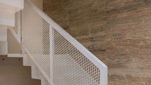 A staircase with a white metal railing, wooden steps, and a wooden wall.