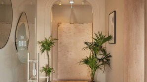 A hallway with a wooden floor, a white reception desk, potted plants, and a sign reading 'CASA TRAVI BOUTIQUE'.