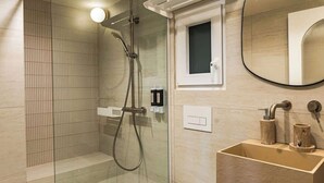 Un bany modern amb dutxa de vidre, un tocador de fusta i un mirall.