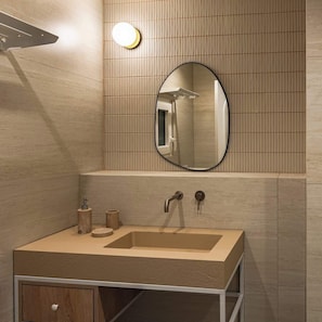 A modern bathroom with a beige sink, a round mirror, and a wall-mounted light fixture.