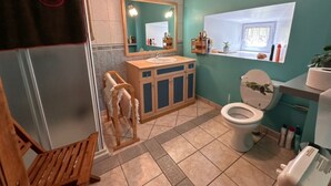 Un baño con banca de madera, lavamanos, inodoro y espejo.