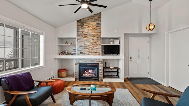 Una sala de estar con chimenea, muebles modernos y ventilador de techo.