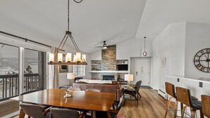 Amplia sala de estar con una mesa de comedor de madera, asientos cómodos, chimenea y un ventanal con vistas al exterior.