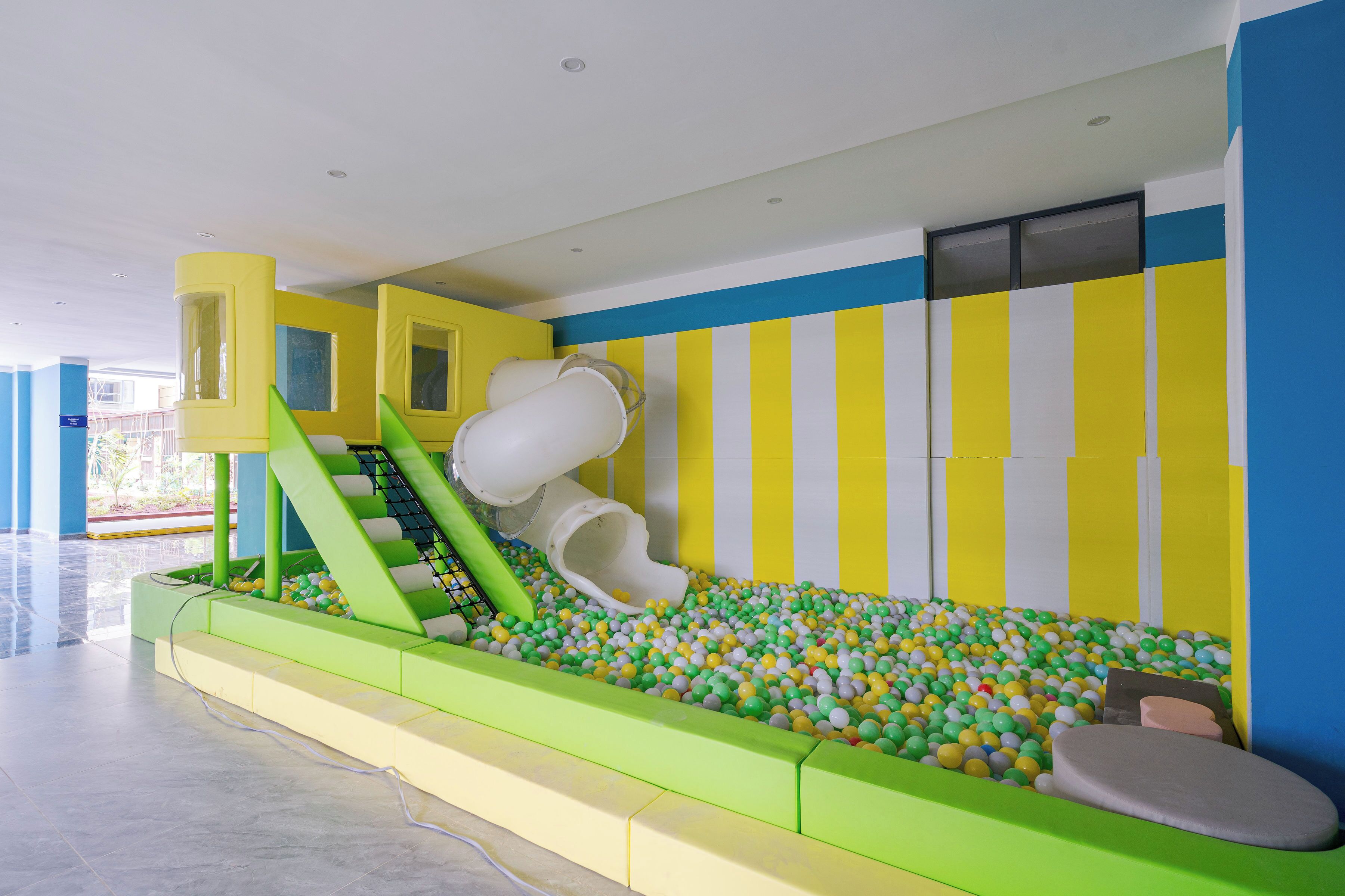 Uma área de recreação com piscina de bolinhas, escorregadores e estruturas para escalar.