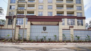 Un edificio de varios pisos con entrada porticada, una placa y una serie de ventanas.