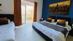 A hotel room with two beds, a large painting on the wall, and a balcony with curtains. - 8Villa (St. Julian's)