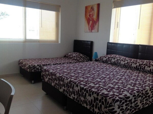 A room with two beds, a chair, and a painting on the wall. - 8Villa (St. Julian's)