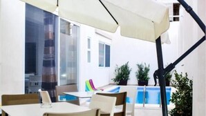 An outdoor patio area with a pool, dining tables, and chairs. - 8Villa (St. Julian's)