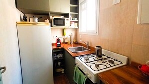 Une cuisine compacte équipée d’un réfrigérateur, d’un four à micro-ondes, d’un évier et d’une cuisinière.