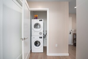 A laundry room with stacked washing machines and a detergent dispenser.