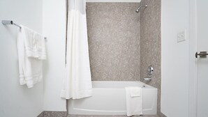 Een moderne badkamer met een badkuip, douche en een handdoekrek met twee handdoeken.