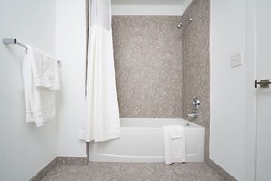 Une salle de bain moderne équipée d’une baignoire, d’une douche et d’un porte-serviettes avec deux serviettes.
